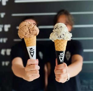 Dolce Amore  The scene also includes two girls holding gelatos on waffle cones. The tags associated with the image are ice cream, dairy, food, dessert, person, ice cream cone, frozen dessert, gelato, snack, holding, and indoor.