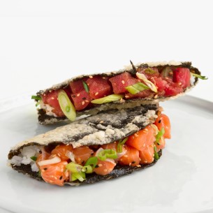 A nori taco with salmon, topped with green onion