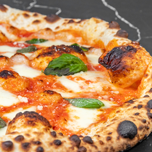 The image is a close-up, overhead shot of a Neapolitan-style pizza. The pizza is the primary focus and fills most of the frame, positioned slightly off-center to the right.