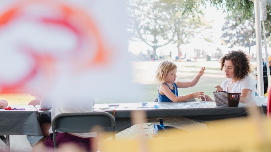 A woman and a children gather around a table doing kids craft activities