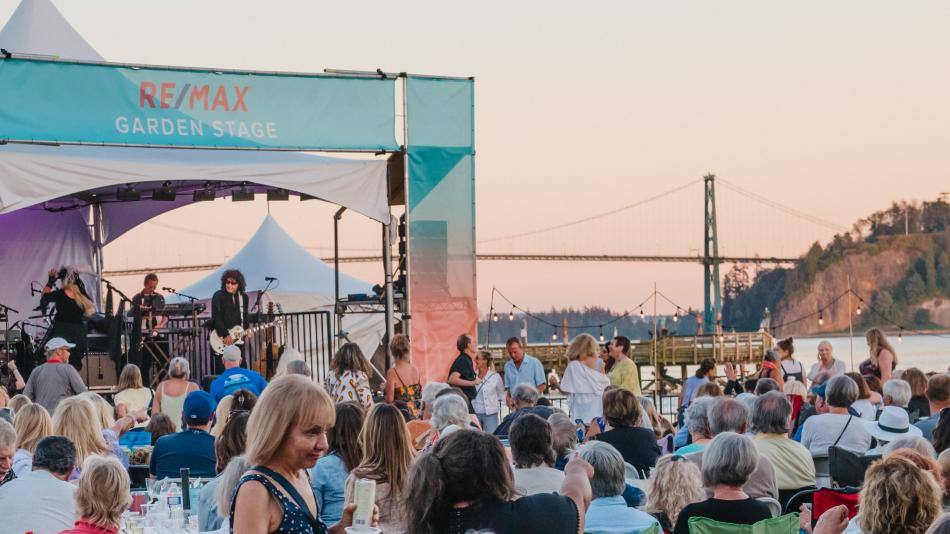  A vibrant crowd enjoying an outdoor concert, immersed in music and lively atmosphere under a clear sky.