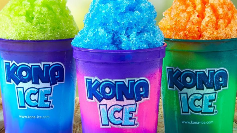 Three colorful cups of shaved Kona ice are placed on a rustic wooden table.