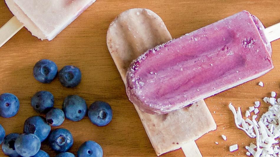 A group of colorful popsicles is displayed, featuring strawberries and coconut shavings on their surfaces. The scene includes fresh strawberries, emphasizing a fruity and refreshing theme. It captures a delightful food moment, ideal for warm days or special occasions.