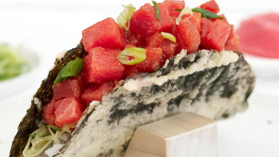 A nori taco with salmon, topped with green onion