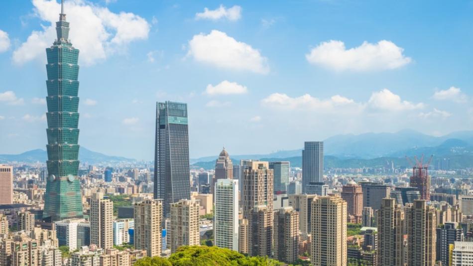 The photo is of a cityscape in Taiwan featuring tall buildings against a backdrop of clouds and sky. The urban area includes skyscrapers and tower blocks, creating a metropolitan landscape.