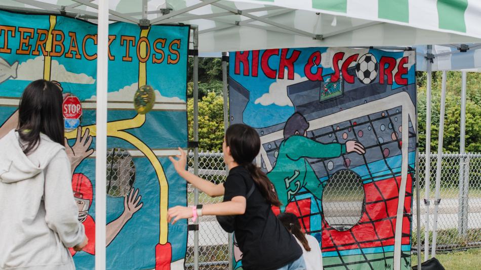 A person and a child are playing together in a play area, enjoying outdoor activities. The scene captures the joy of their interaction. The tags associated with this image include clothing, art, painting, and street-related elements.