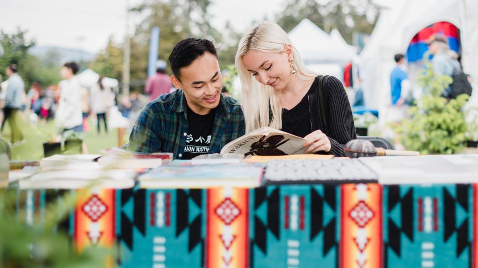 A couple seated at a table, engrossed in reading a book together, sharing a moment of connection and learning