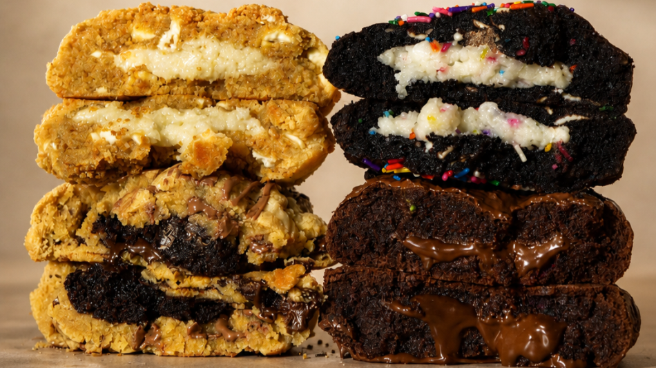 The image showcases a visually appealing arrangement of four decadent cookies, halved and stacked to reveal their rich fillings. The cookies are presented in two vertical stacks, side-by-side, against a muted, neutral background with a subtle texture, possibly parchment paper or a lightly textured wall. The lighting is soft and directional, casting gentle shadows that add depth and dimension to the scene.