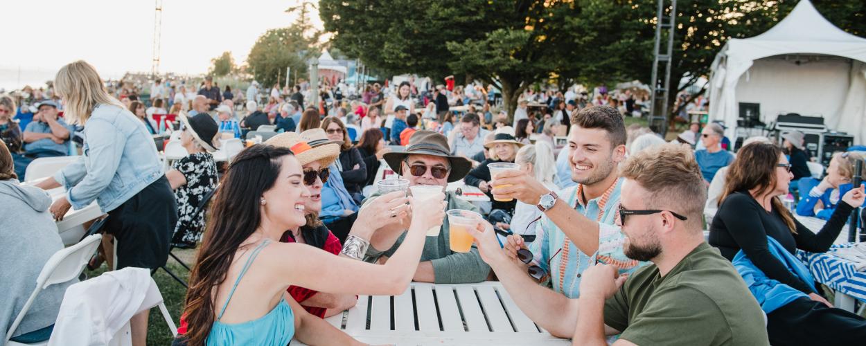 A lively concert crowd enjoying the music, with family and friends raising their glasses for a toast at the Park Royal Beachside Patio.