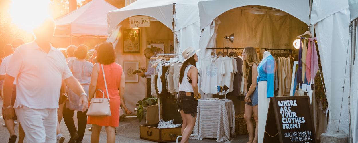 A group of shoppers navigating through a busy market, engaging with vendors and exploring various products.