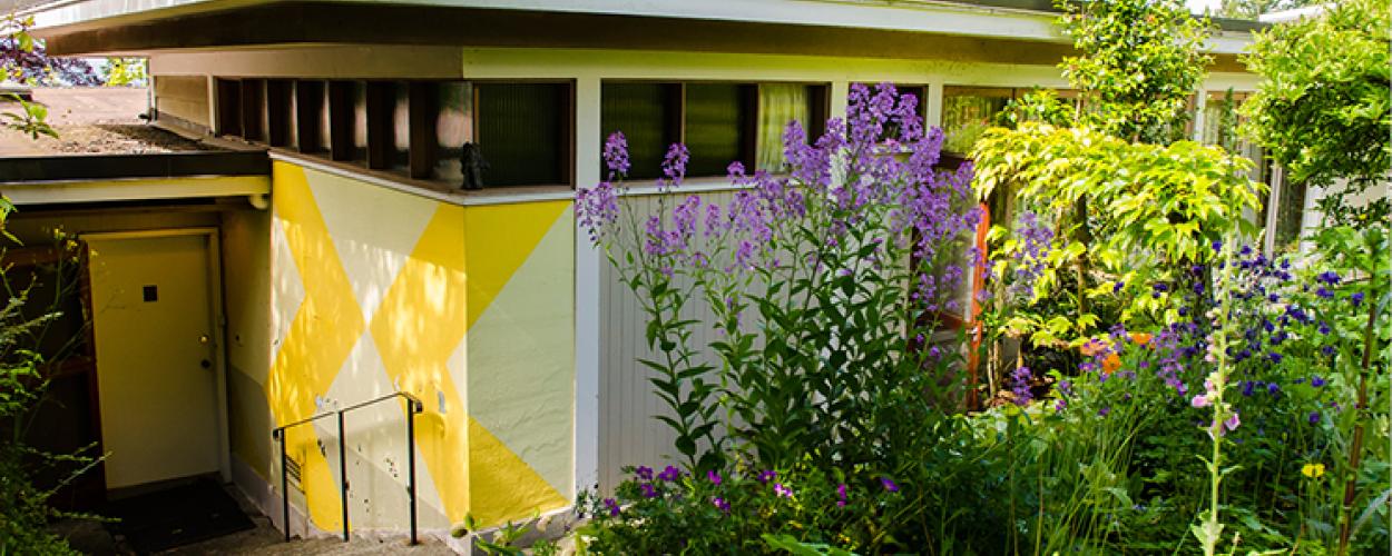The Binning Residence entrance, set into the ground and surrounded by foliage.