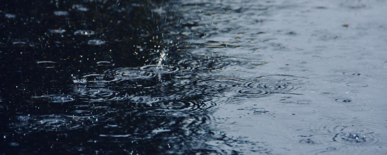 Raindrops splashing onto flooded pavement.