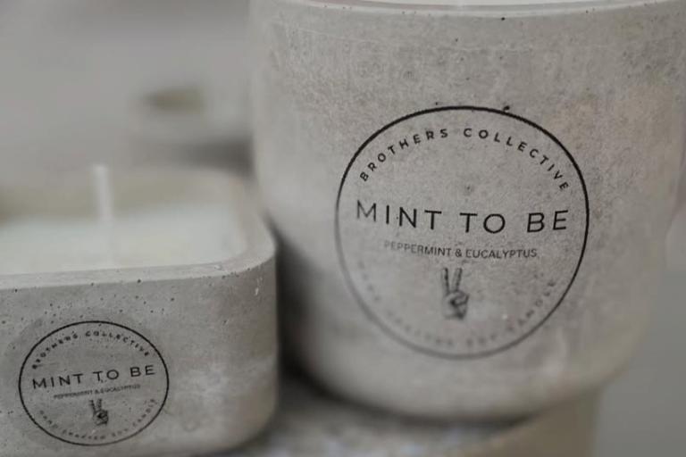 The image is a close-up of a container that holds a blend of two types of mint: "Collectivy Broth Mint" and "Eucalyptis Mint." The container appears to be part of indoor tableware, likely made for serving coffee or other beverages. It showcases the text related to the contents, emphasizing its unique flavors.