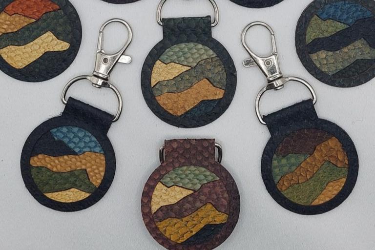 The image displays a collection of round keychains with a landscape design. The keychains are arranged on a plain white or light gray surface, suggesting a studio or display setting.