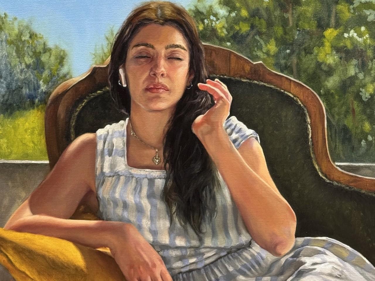 This is a realistic oil painting of a young woman with dark hair and medium skin tone, sitting outdoors and appearing to be listening to something with white wireless earbuds in her ears. She is positioned slightly off-center to the right, with her eyes closed and a serene expression on her face. Her head is tilted slightly back, and her right hand is raised near her face, with her fingers delicately touching her hair. She is wearing a light blue and white striped sundress with a square neckline. Around her
