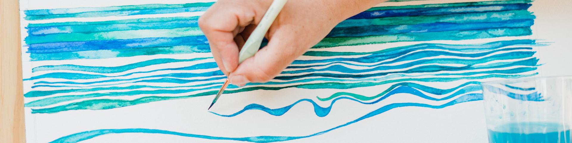 A hand is holding a paintbrush, ready to create art. The scene captures the essence of creativity and expression, likely involving a child's engagement with drawing or painting. The content emphasizes themes related to art and sketching.