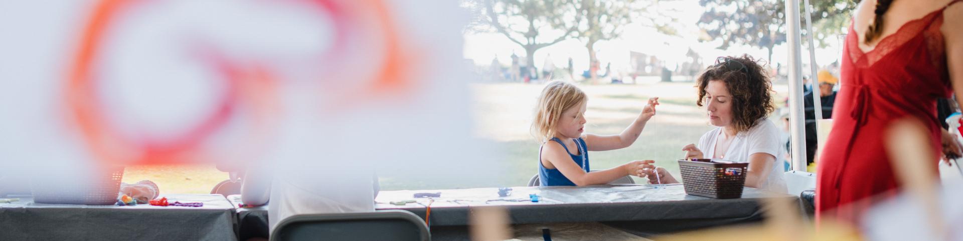A woman and a children gather around a table doing kids craft activities