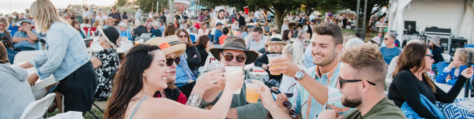 A lively concert crowd enjoying the music, with family and friends raising their glasses for a toast at the Park Royal Beachside Patio.