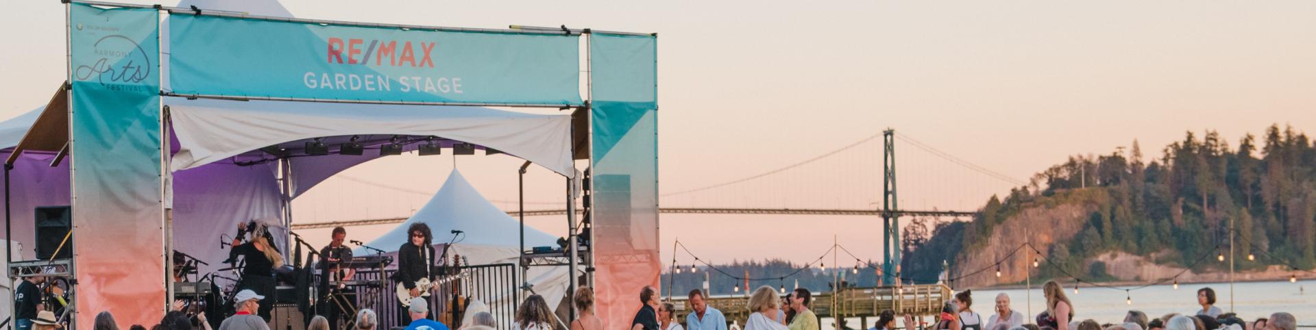  A vibrant crowd enjoying an outdoor concert, immersed in music and lively atmosphere under a clear sky.