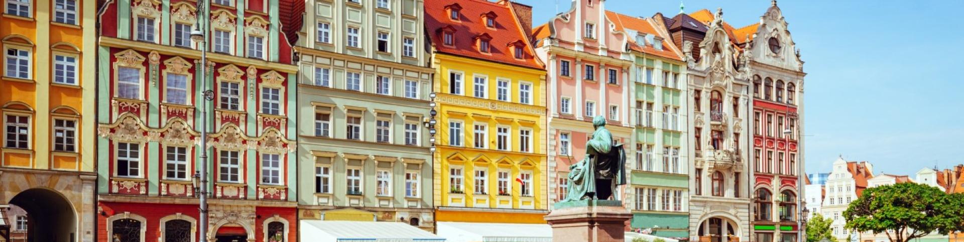 The photo is of a statue in front of a building in Wroclaw, Poland. The building appears to be historic tenements on the main square.