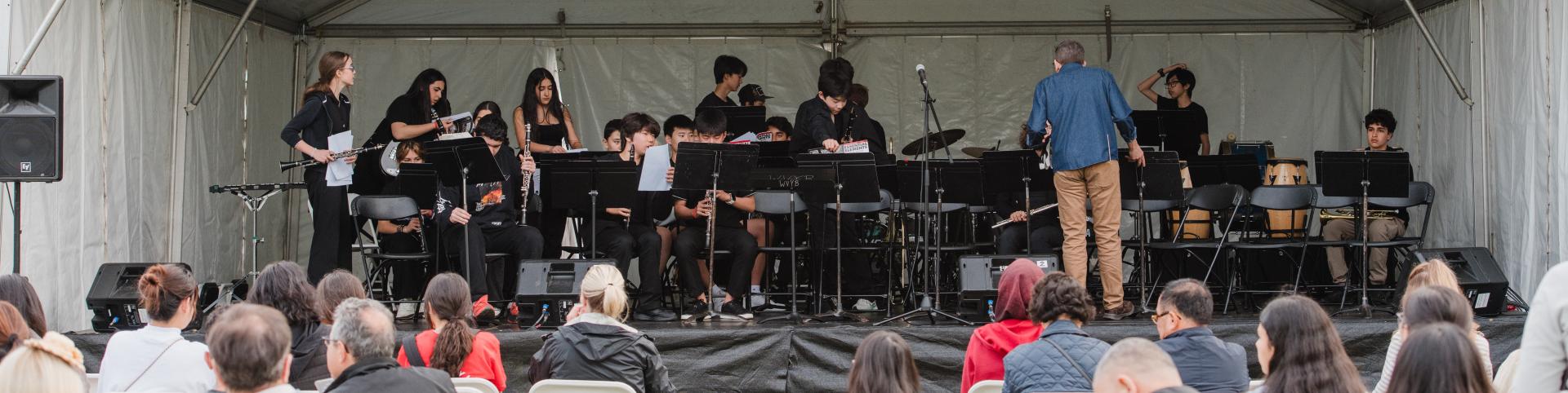 West Vancouver Schools’ stage with the school orchestra playing and the crowd watching
