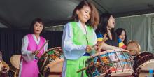 A group of women playing traditional Korean drums at a vibrant festival, showcasing their cultural performance and unity.